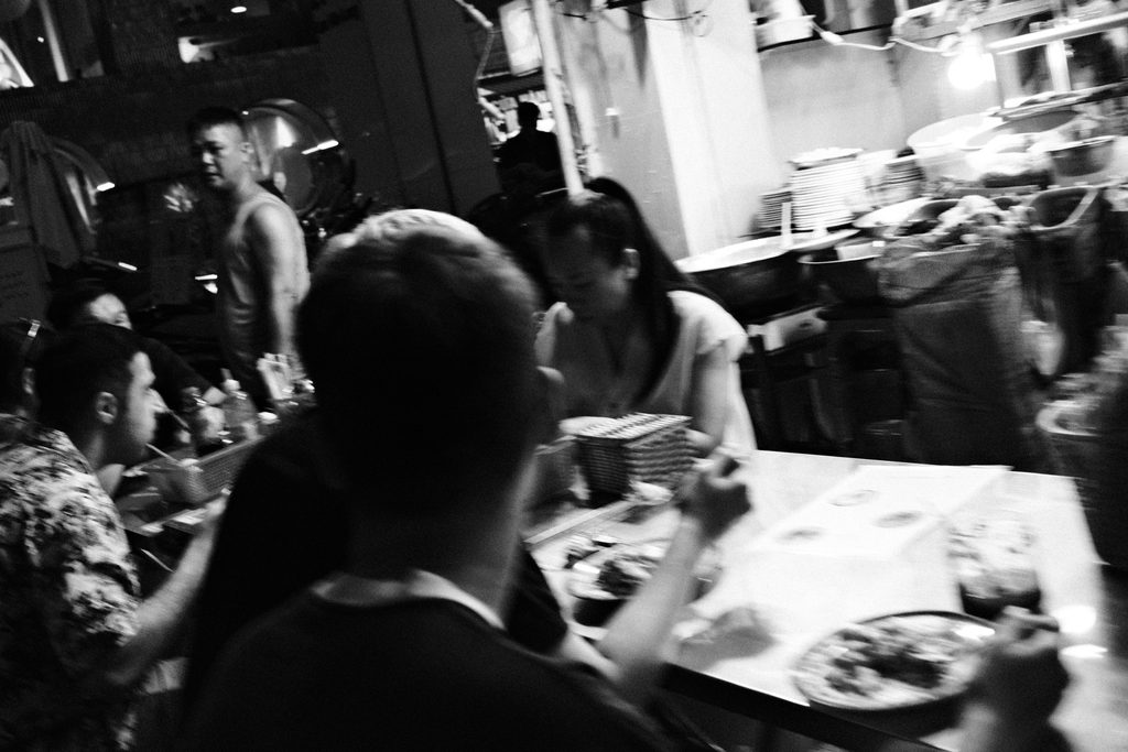 Convives attablés dans un restaurant bondé, assiettes et verres sur la table