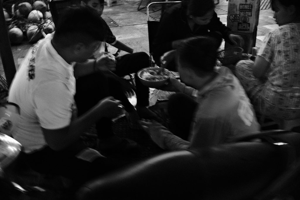Hommes attablés serrés entre les motos, autour d'un repas de rue au Vietnam