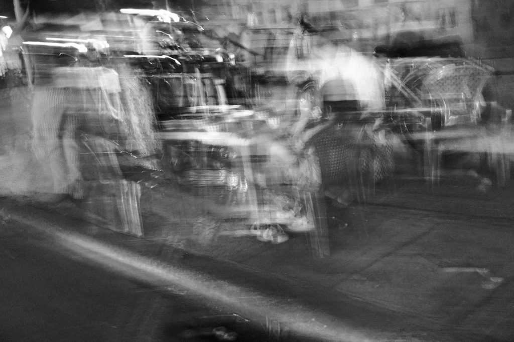 Rue de nuit traversée de silhouettes et de lumières en mouvement