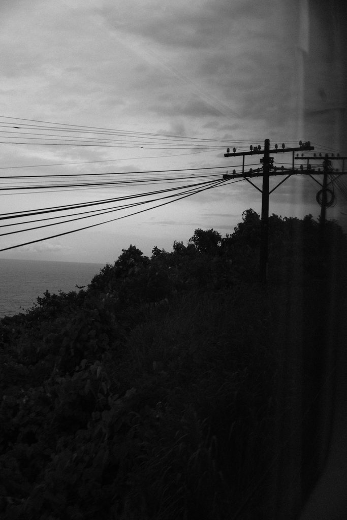 Poteau électrique au sommet d'une colline boisée, vu à travers la vitre du train