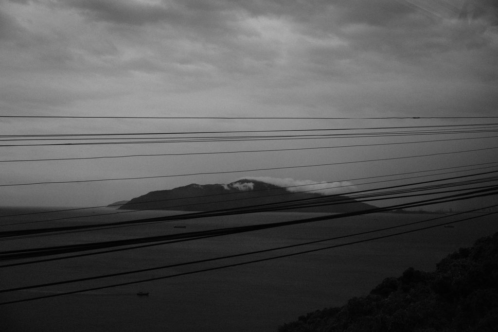 Île montagneuse au large, vue à travers les câbles électriques depuis le train