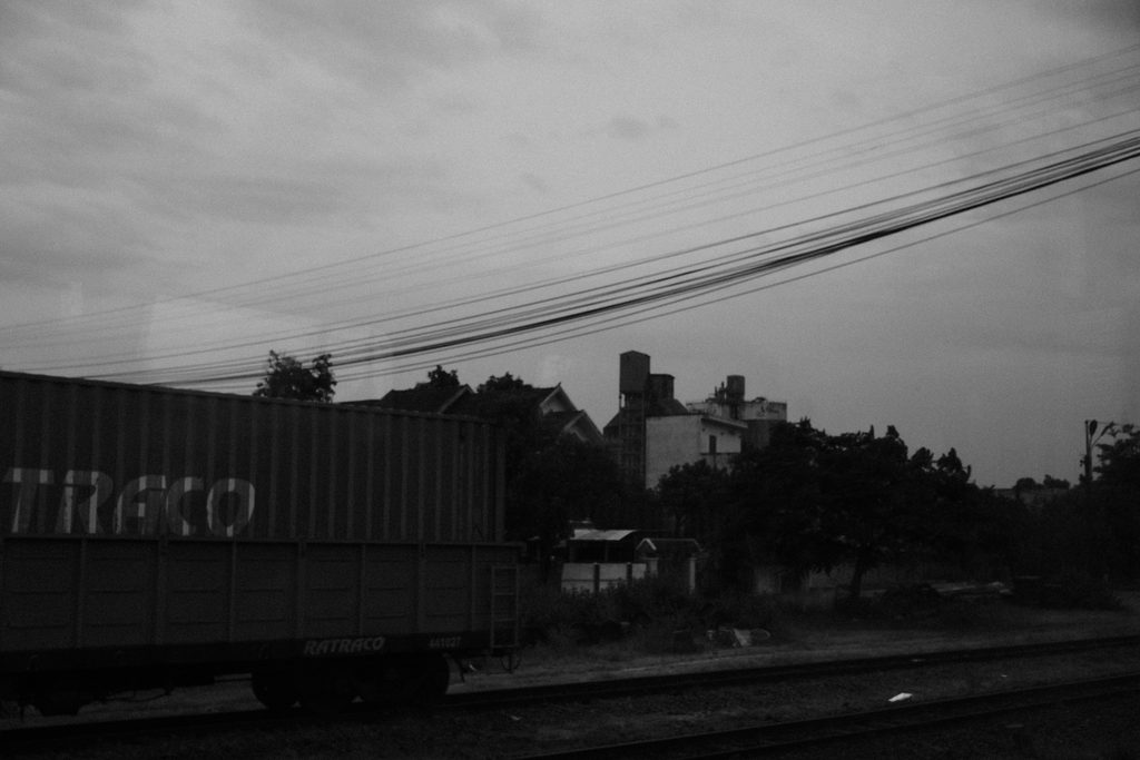 Conteneur et lignes électriques sous un ciel gris, à l'approche d'une ville
