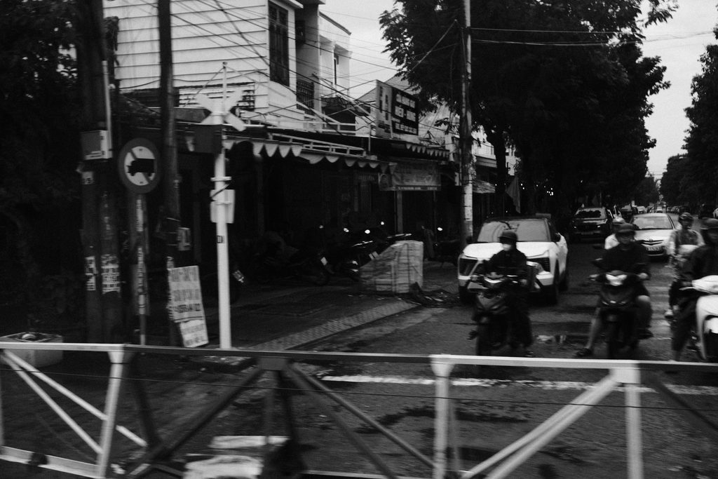 Passants et motos attendant derrière la barrière d'un passage à niveau