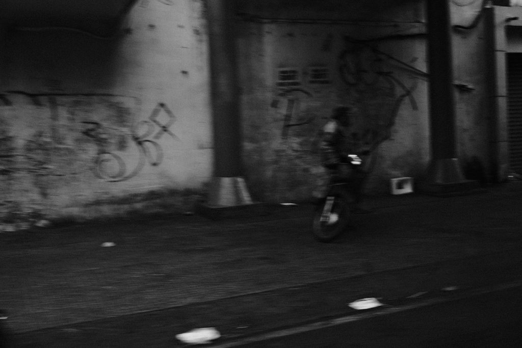 Silhouette à vélo sous un pont aux piliers tagués