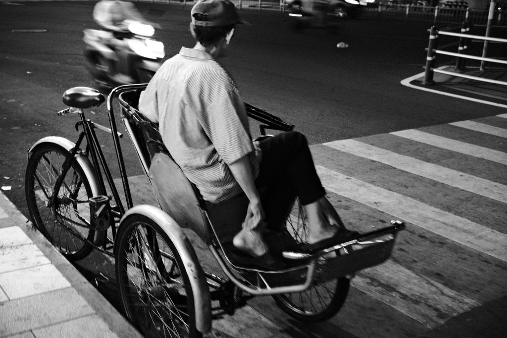 Conducteur de cyclo-pousse traversant un passage piéton la nuit, au Vietnam