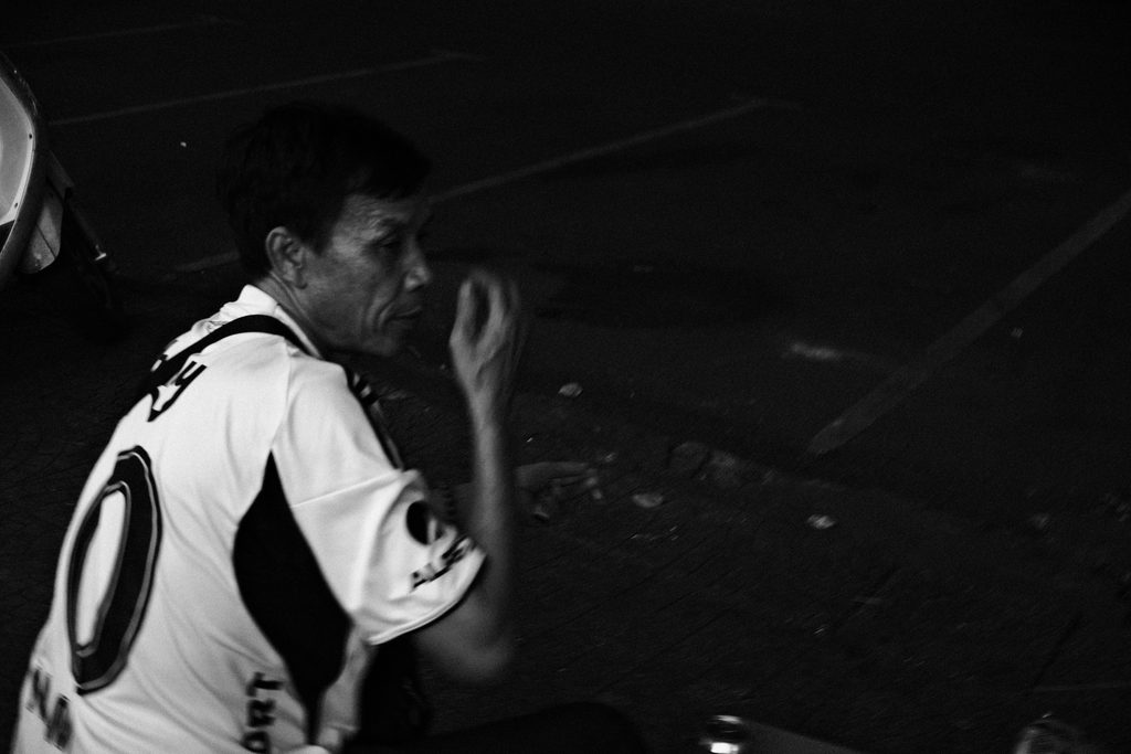Homme en maillot de football, la main devant la bouche, dans la rue la nuit